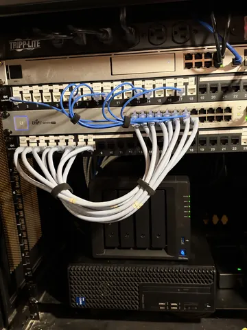 After: the same cabinet rebuilt with Cat6 patch panels, a UniFi switch and short patch cables bundled and tied