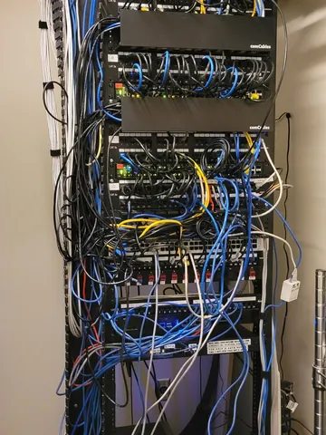 Before: floor-standing network rack with tangled patch cords between the panels