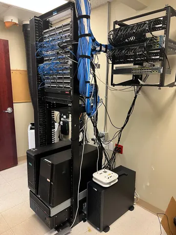 After: the same network closet re-patched, with cable bundles routed and secured down the rack