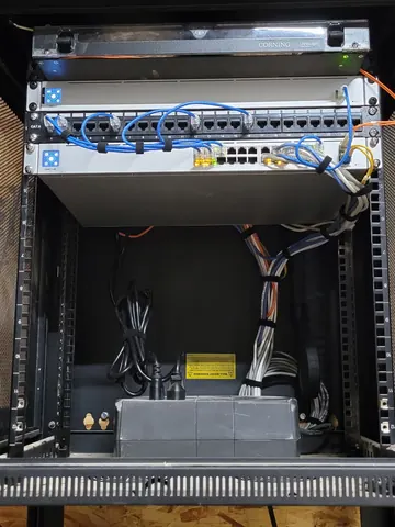 Compact network rack with a switch and patch panel on a shelf above the equipment